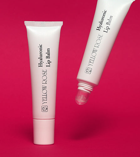 Två tuber Yellow Rose Hyaluronic Lip Balm mot mörkrosa bakgrund